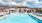 Apartments In Reno For Rent - Vida - Resort-Style Swimming Pool, Sundeck, Lounge Chairs, Plush Couches, And Resident Building In The Background